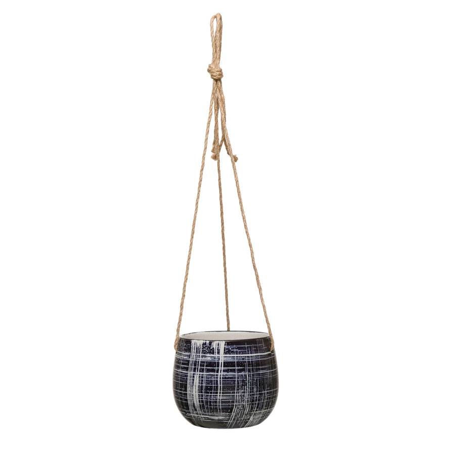 A dark blue stoneware hanging planter with white hatching patterns and a natural jute hanger.